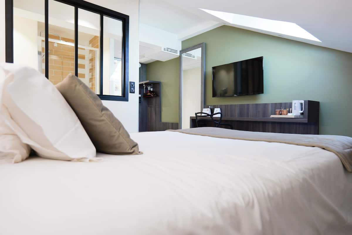 Hotelkamer met een groot bed, een flatscreen televisie aan de muur, een koffieapparaat en uitzicht door een raam.