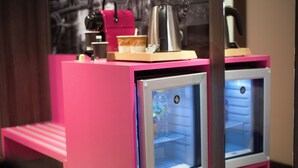 A pink minibar with a coffee maker, a glass of water, and a small tray.