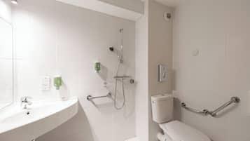 Ein modernes Badezimmer mit Waschbecken, Toilette und Duschkabine mit Haltegriffen.