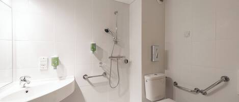 A modern bathroom with a white sink, a toilet, and a shower with grab bars.