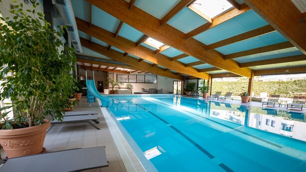 An indoor swimming pool with a wooden ceiling, lounge chairs, and potted plants. - Best Western Le Relais de Laguiole Hotel & Spa (Laguiole)