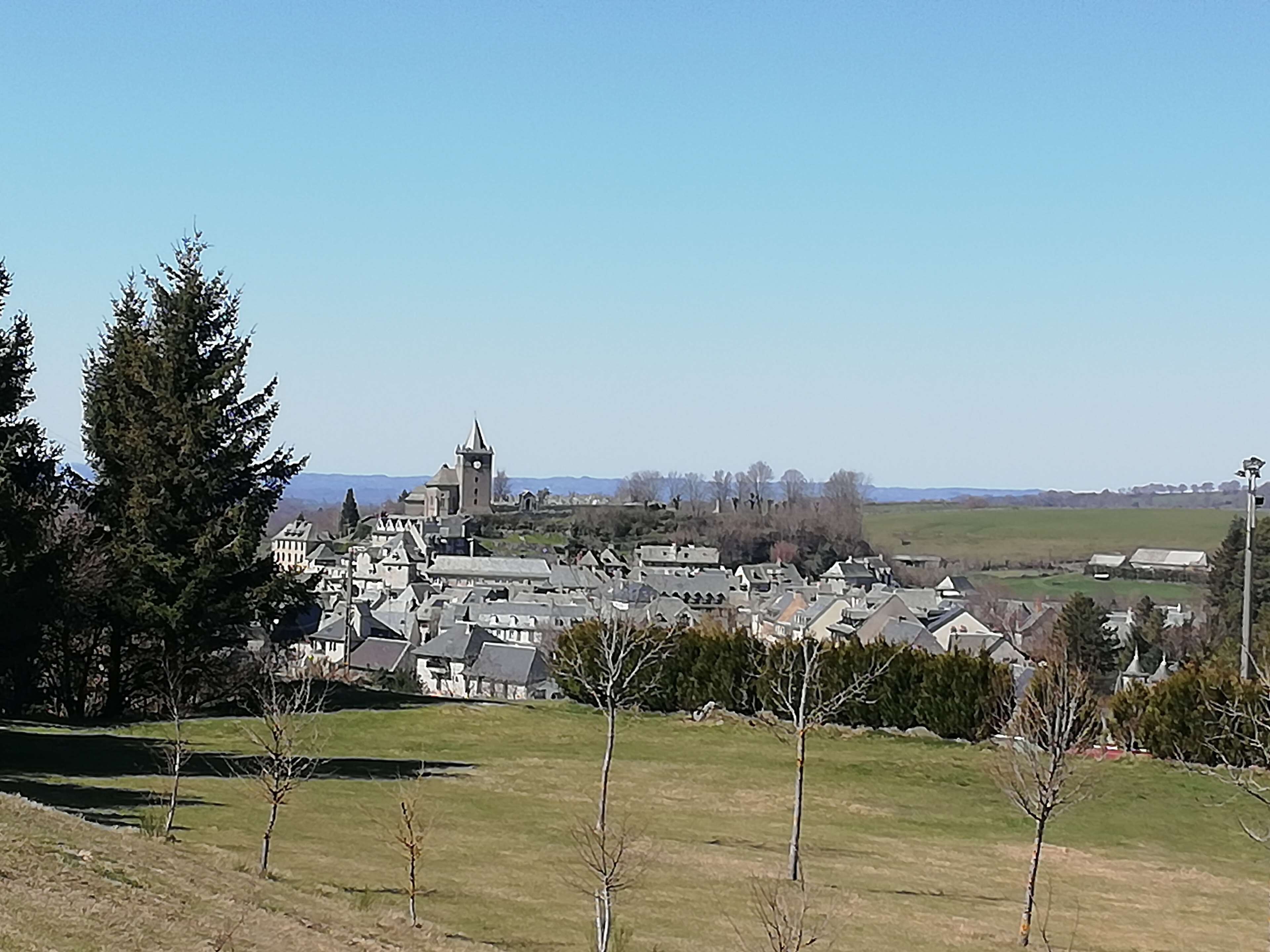 Un pueblo con edificios históricos, una iglesia destacada con un campanario y una vista despejada del paisaje circundante.
