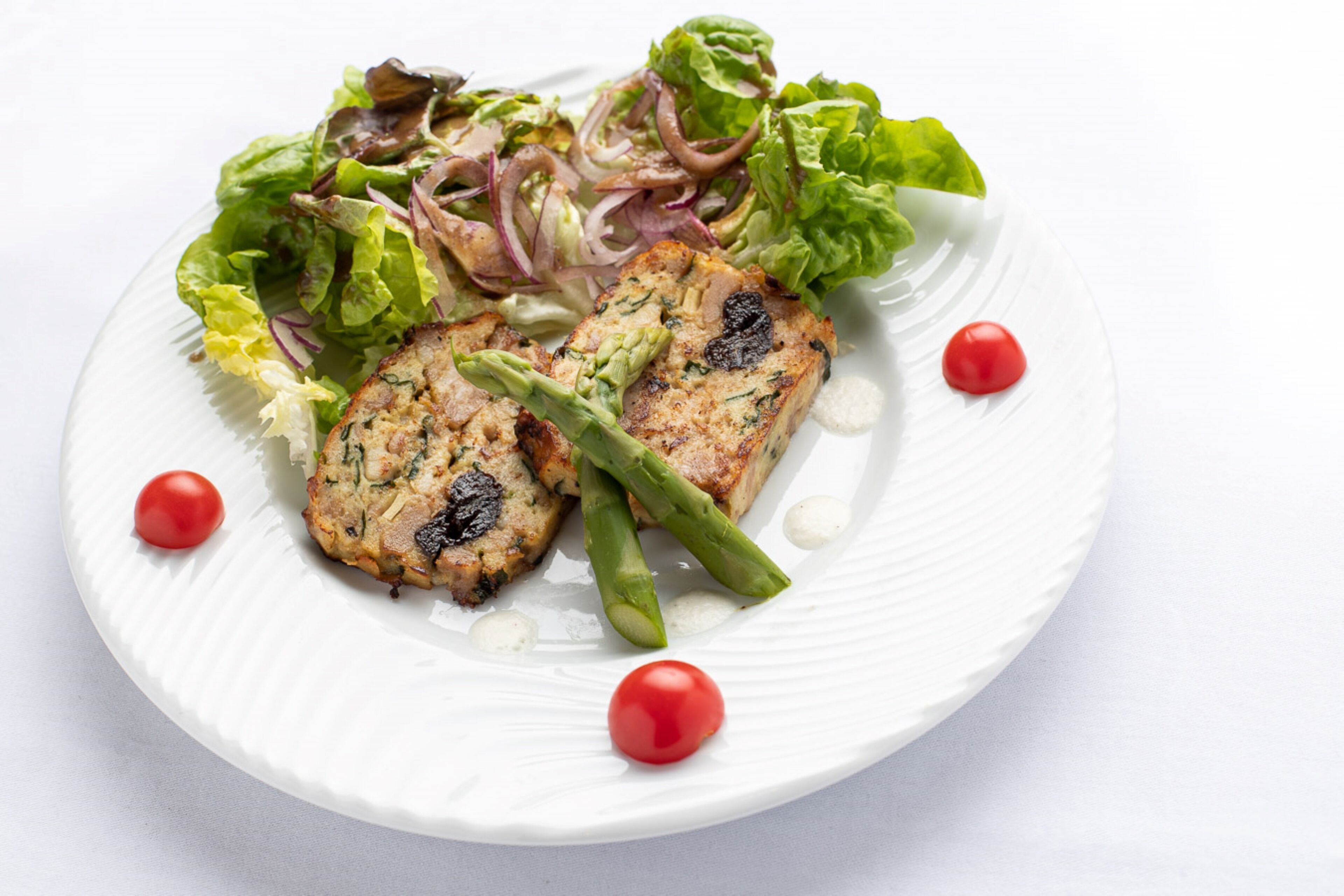 A plate with grilled chicken, asparagus, and a mixed green salad.