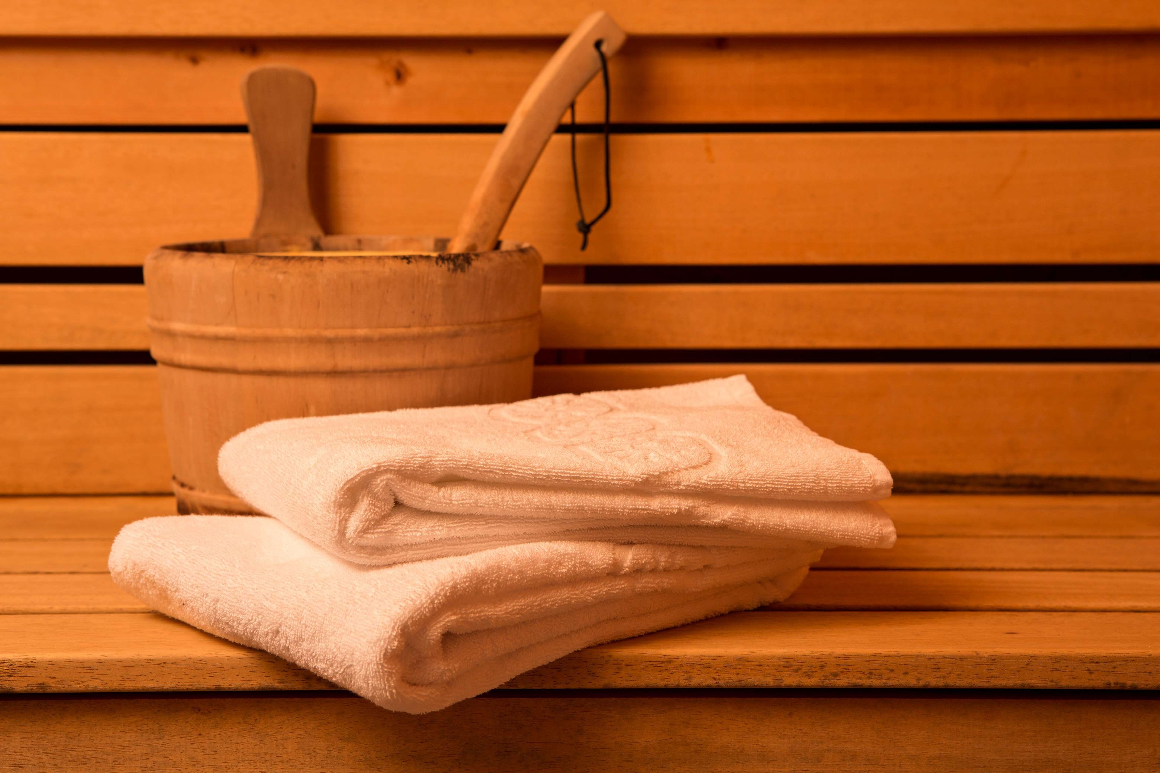 A wooden bench with a stack of folded towels and a wooden bucket with a wooden spoon.