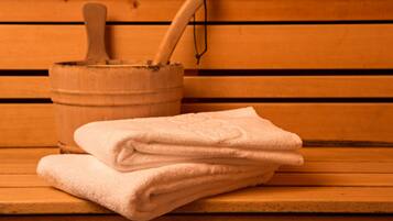 A wooden bench with a stack of folded towels and a wooden bucket with a wooden spoon.