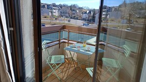 A balcony with a table and chairs, a small potted plant, and a view of a residential area. - Best Western Le Relais de Laguiole Hotel & Spa (Laguiole)