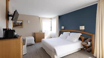 Ein Hotelzimmer mit einem großen Bett, Nachttischen, einem Schreibtisch mit Computer und einem an der Wand montierten Fernseher.