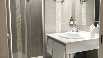 Une salle de bain moderne avec une douche à parois de verre, un lavabo blanc et un grand miroir.