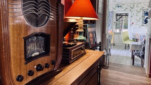 A vintage radio with a clock, a red lamp, and a bookshelf with books and a magazine. - Château Corneille (Le Val d'Hazey)