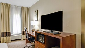 A hotel room with a wooden desk, a flat-screen TV, a lamp, a chair, and a microwave. - Comfort Inn Henderson - Evansville South (Henderson)