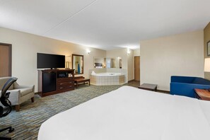 A hotel room with a bed, a desk, a television, a minibar, a bathroom with a bathtub, and a seating area. - Comfort Inn & Suites Branson Meadows (Branson)