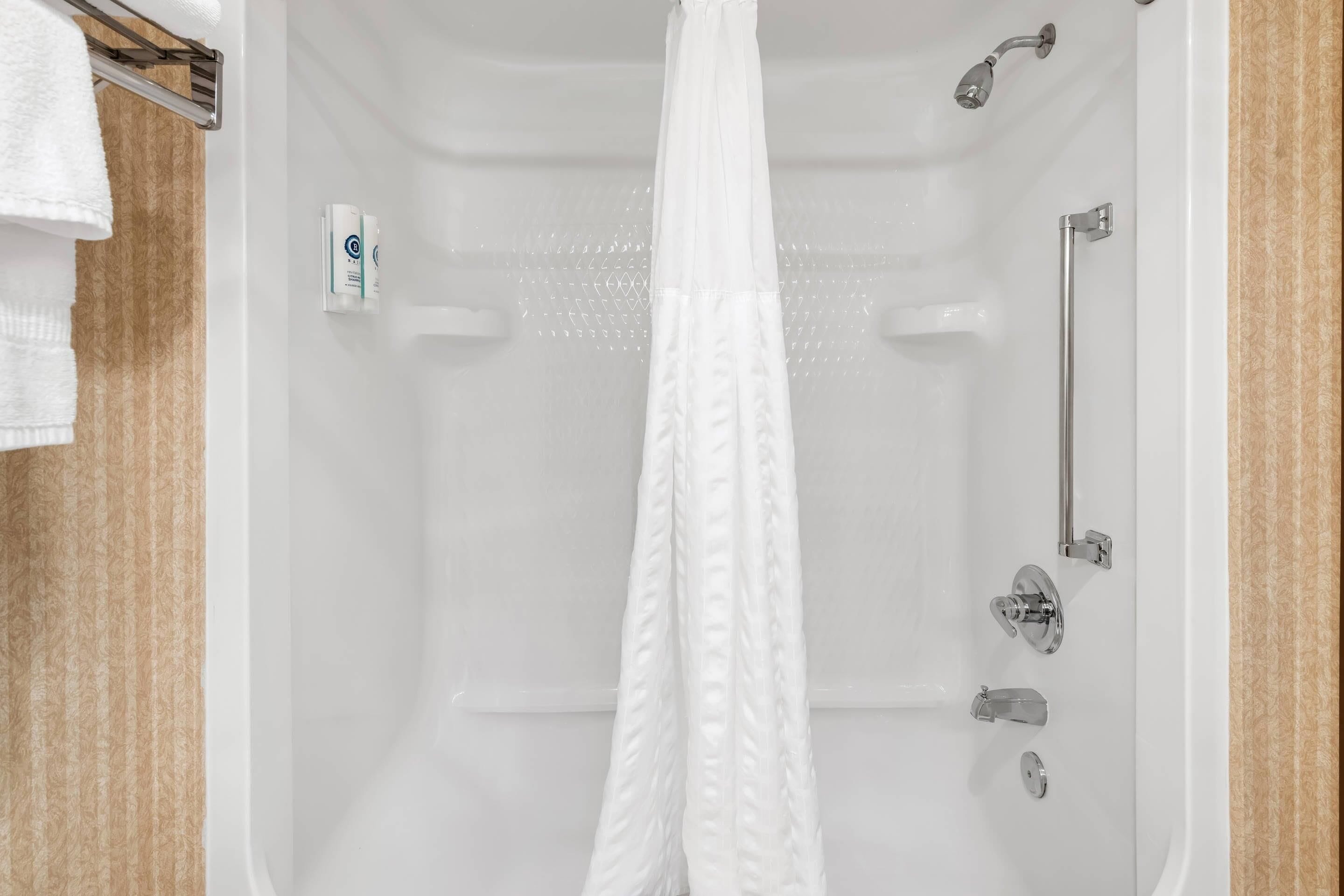 A white bathtub with a shower curtain, a handheld showerhead, and a handheld shower attachment.