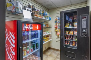 Una máquina expendedora con refrigerios y un refrigerador de Coca-Cola lleno de bebidas.