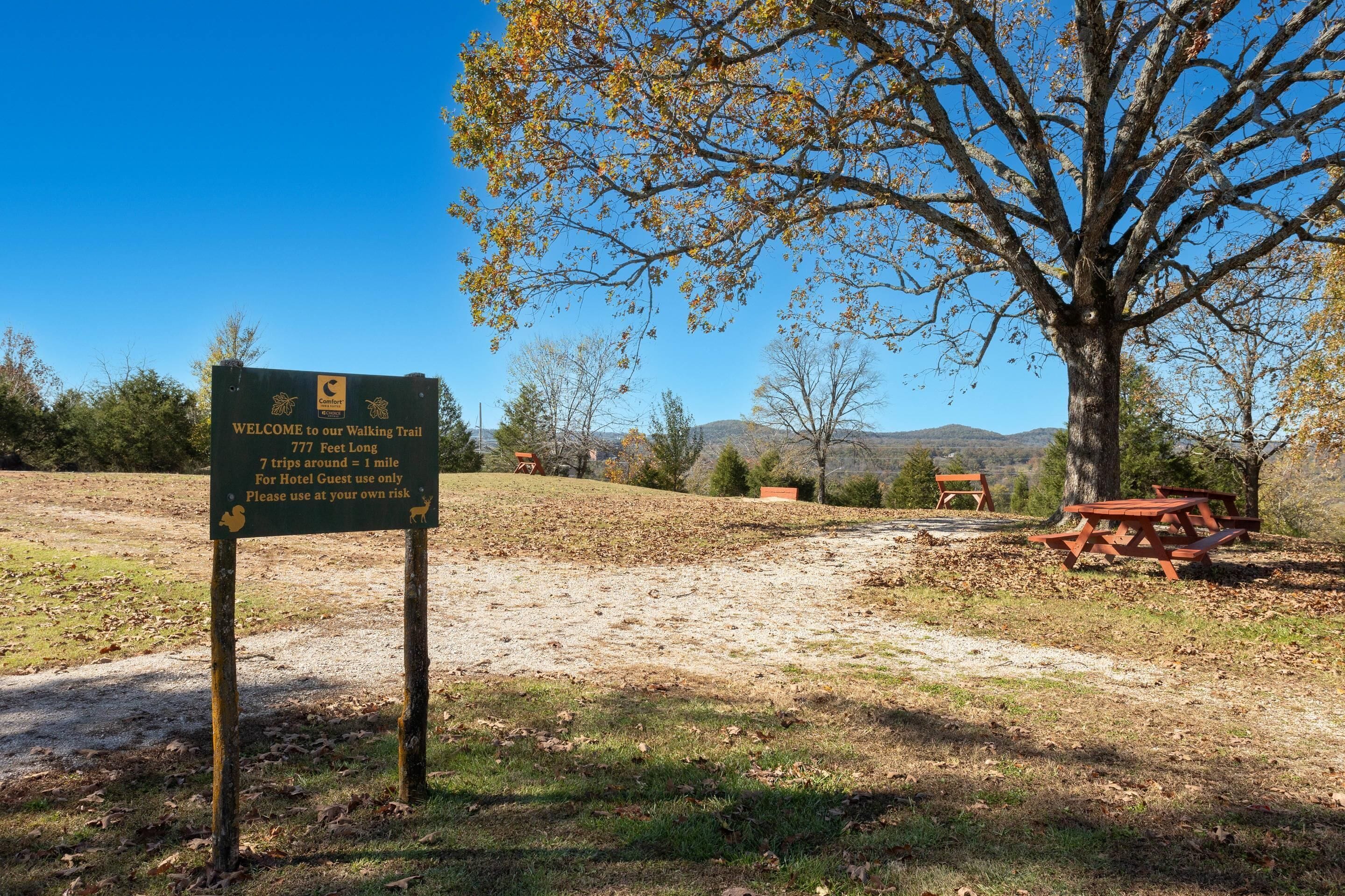 A sign for a walking trail with a clear sky and trees in the background.