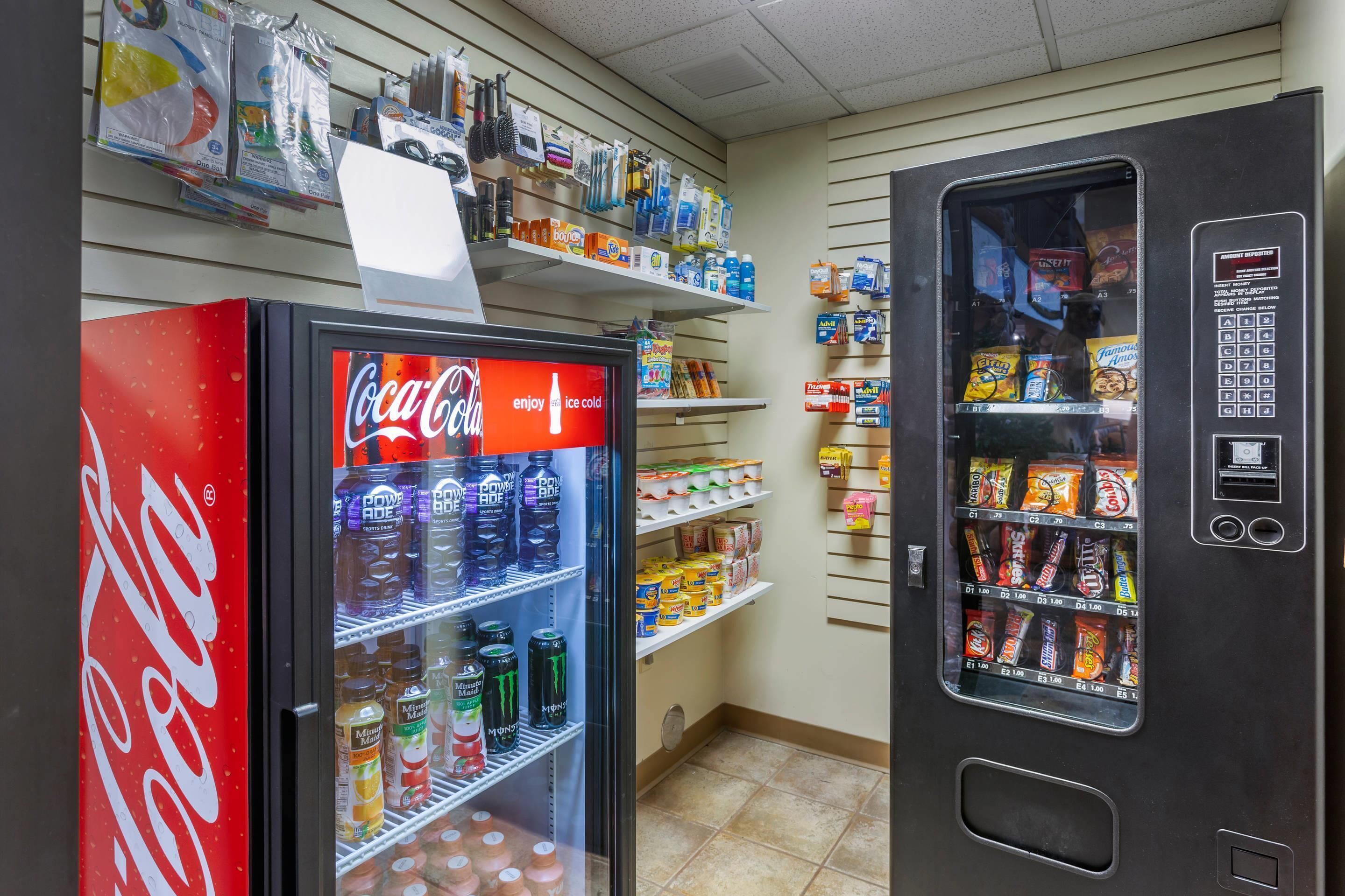 Myyntiautomaatti, jossa on Coca-Colan kylmälaitteella varustettu tila, valikoima juomia ja toinen myyntiautomaatti, josta saa pientä purtavaa.