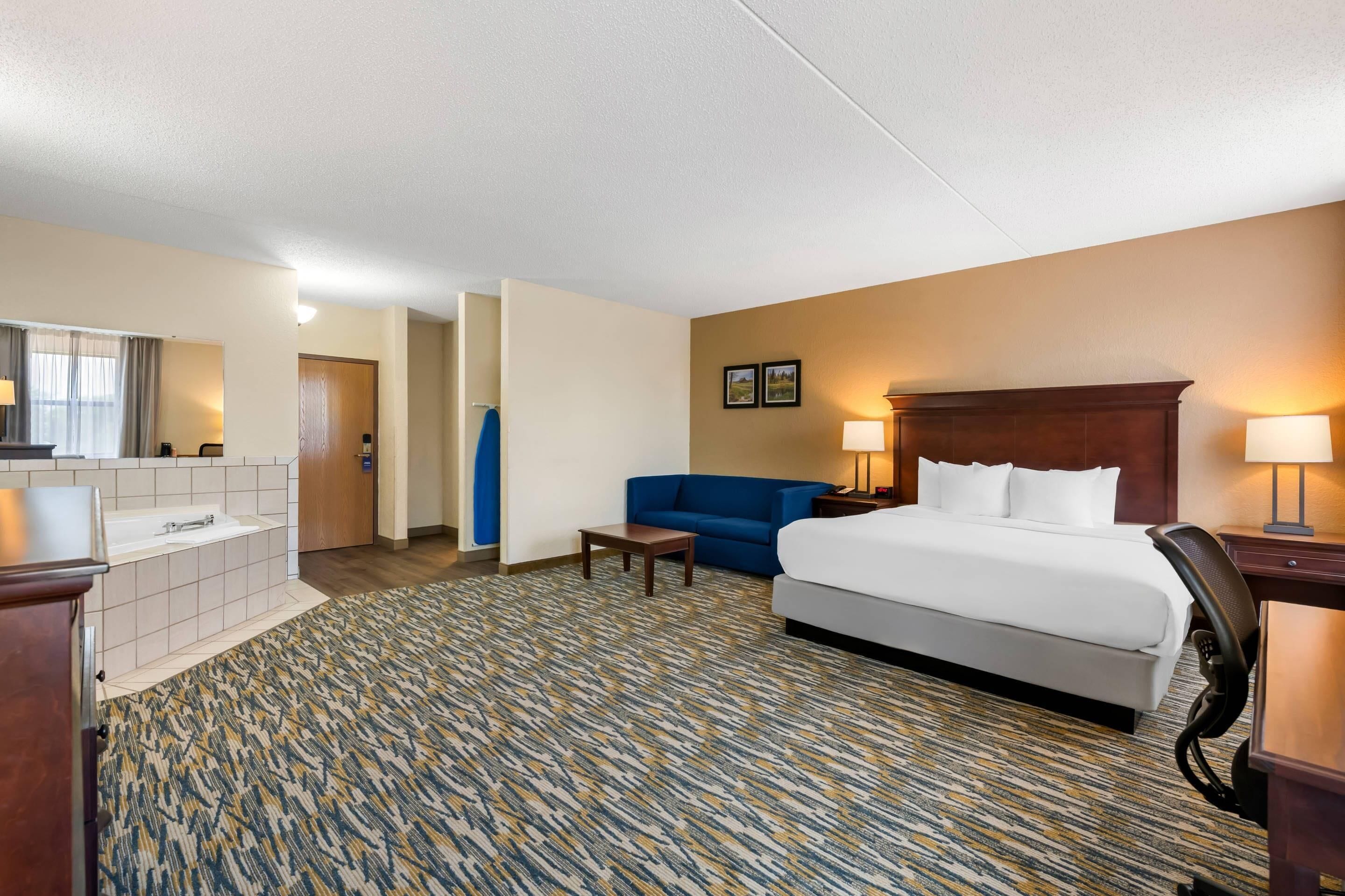 Una habitación de hotel con cama, escritorio, silla, sofá y baño.
