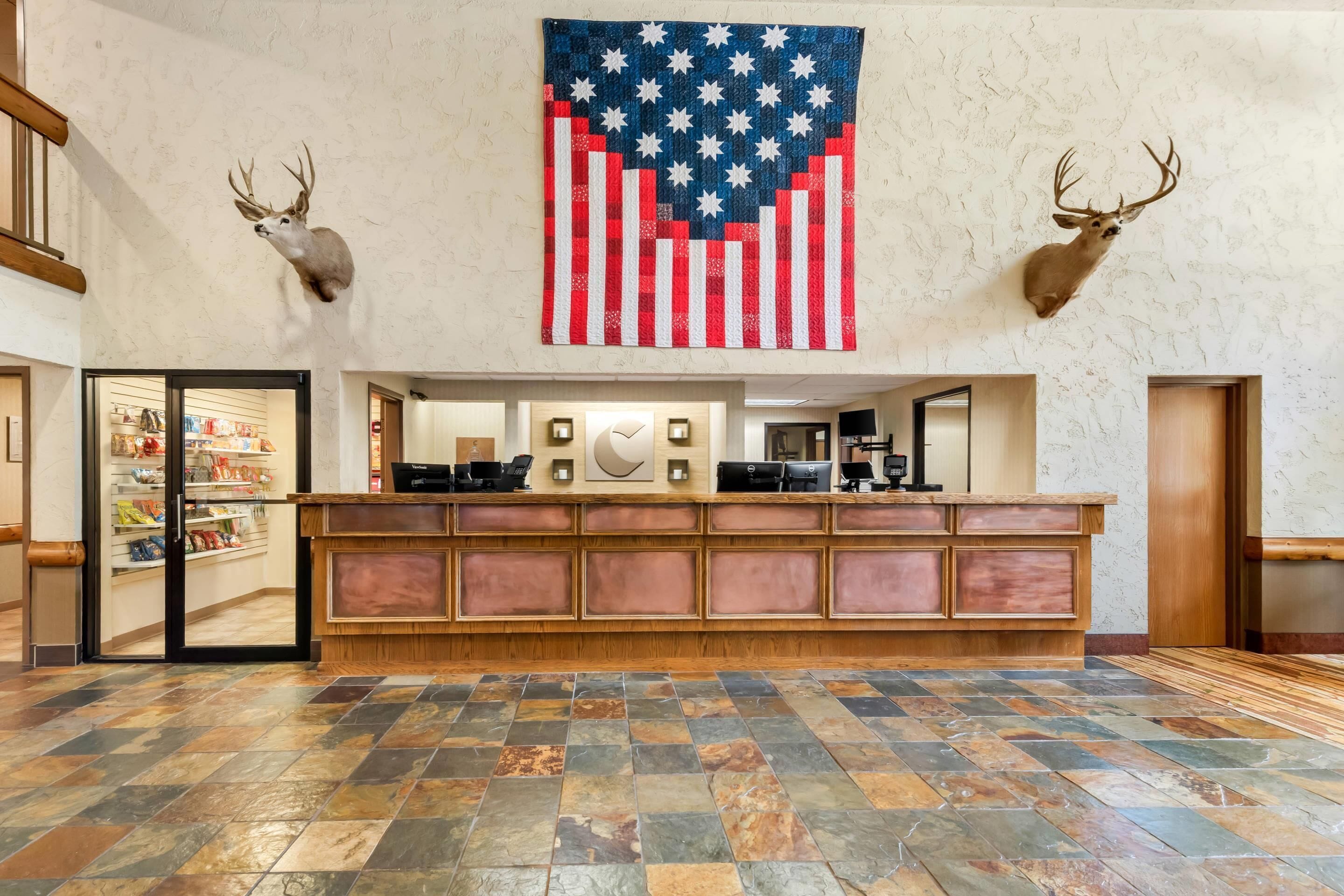 A lobby with a reception desk, mounted deer heads, and an American flag.