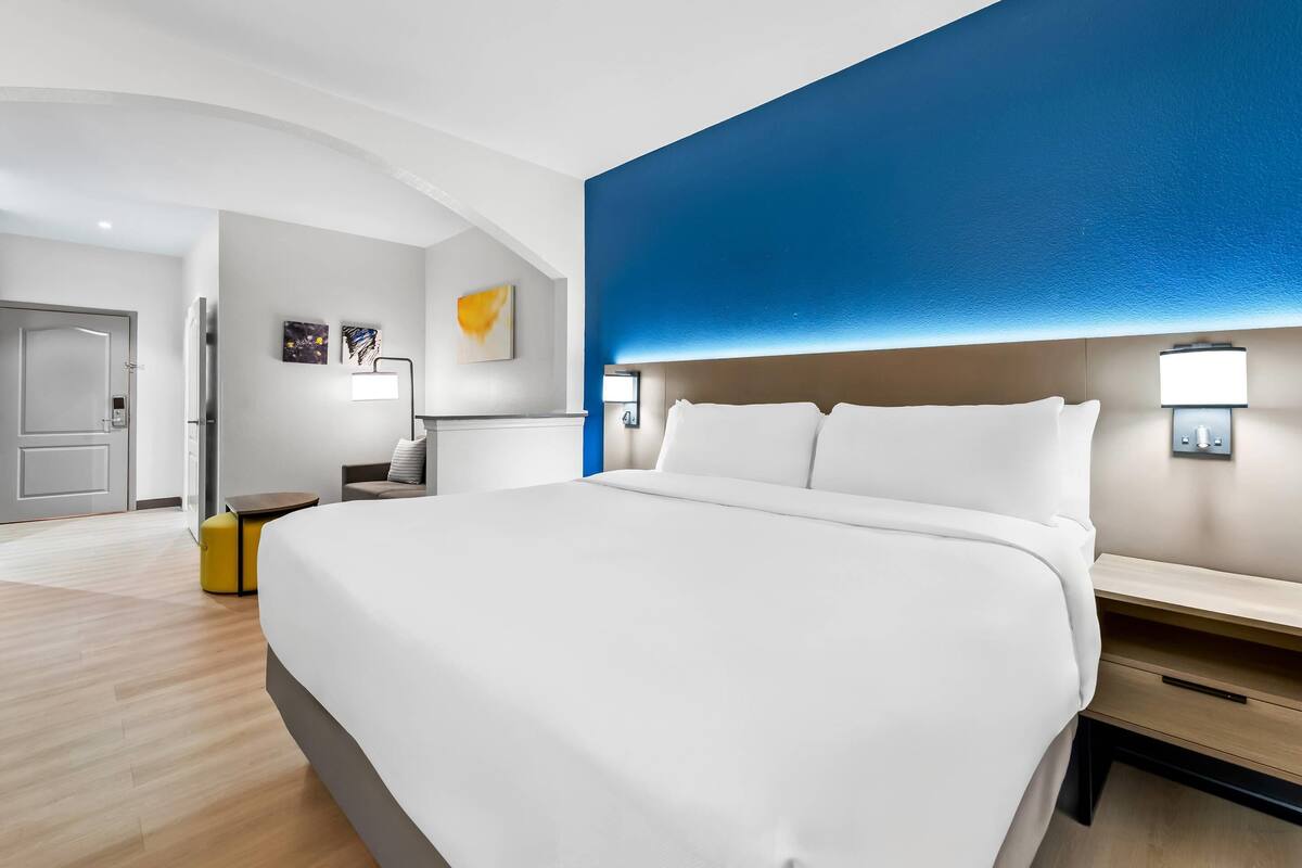 Een moderne hotelkamer met een groot bed, nachtkastjes, een bureau en een stoel.