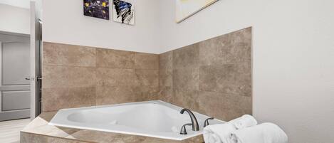 Un baño moderno con una bañera independiente, baldosas color crema y un perchero para toallas.
