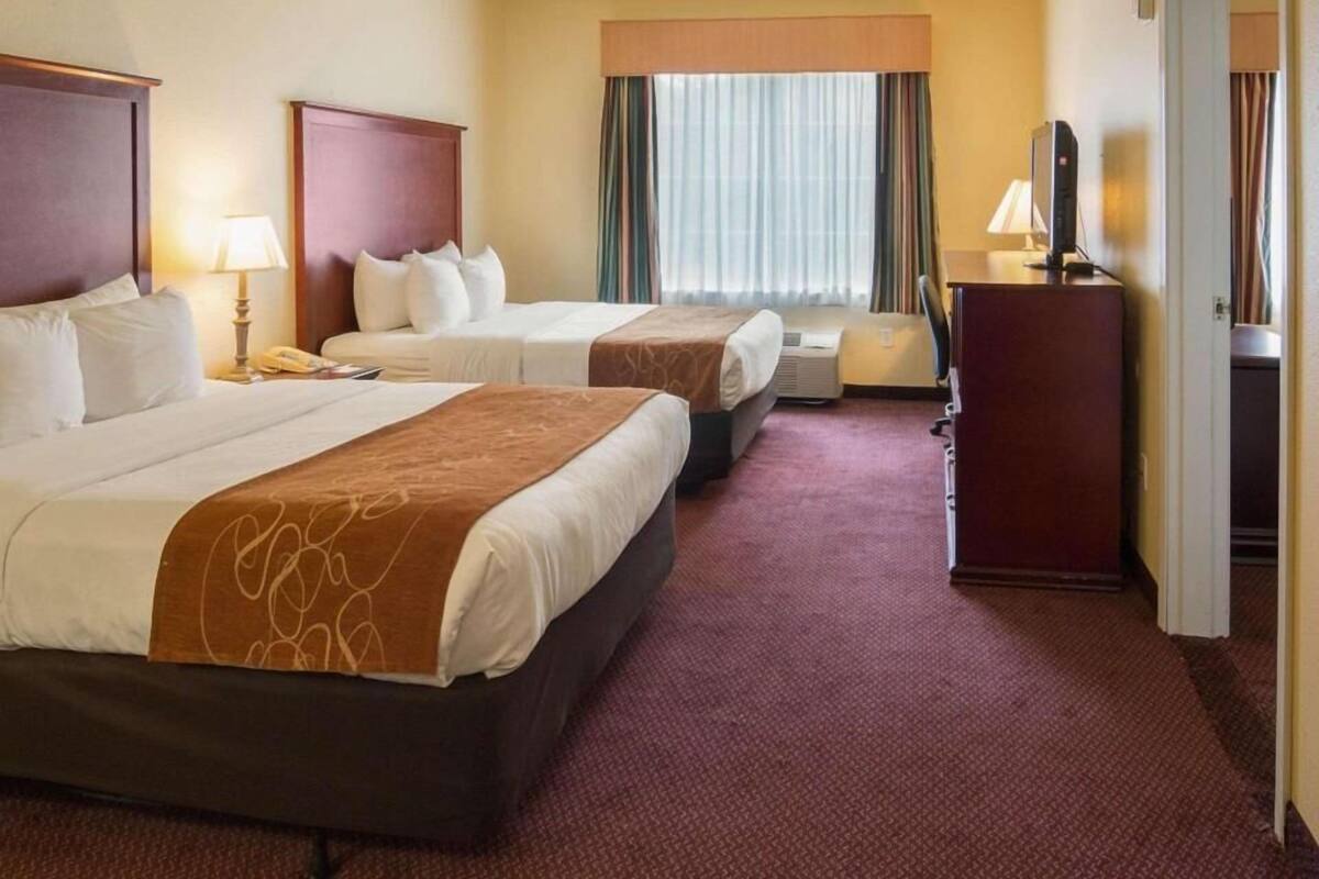 Een hotelkamer met twee bedden, een bureau, een telefoon en een televisie.