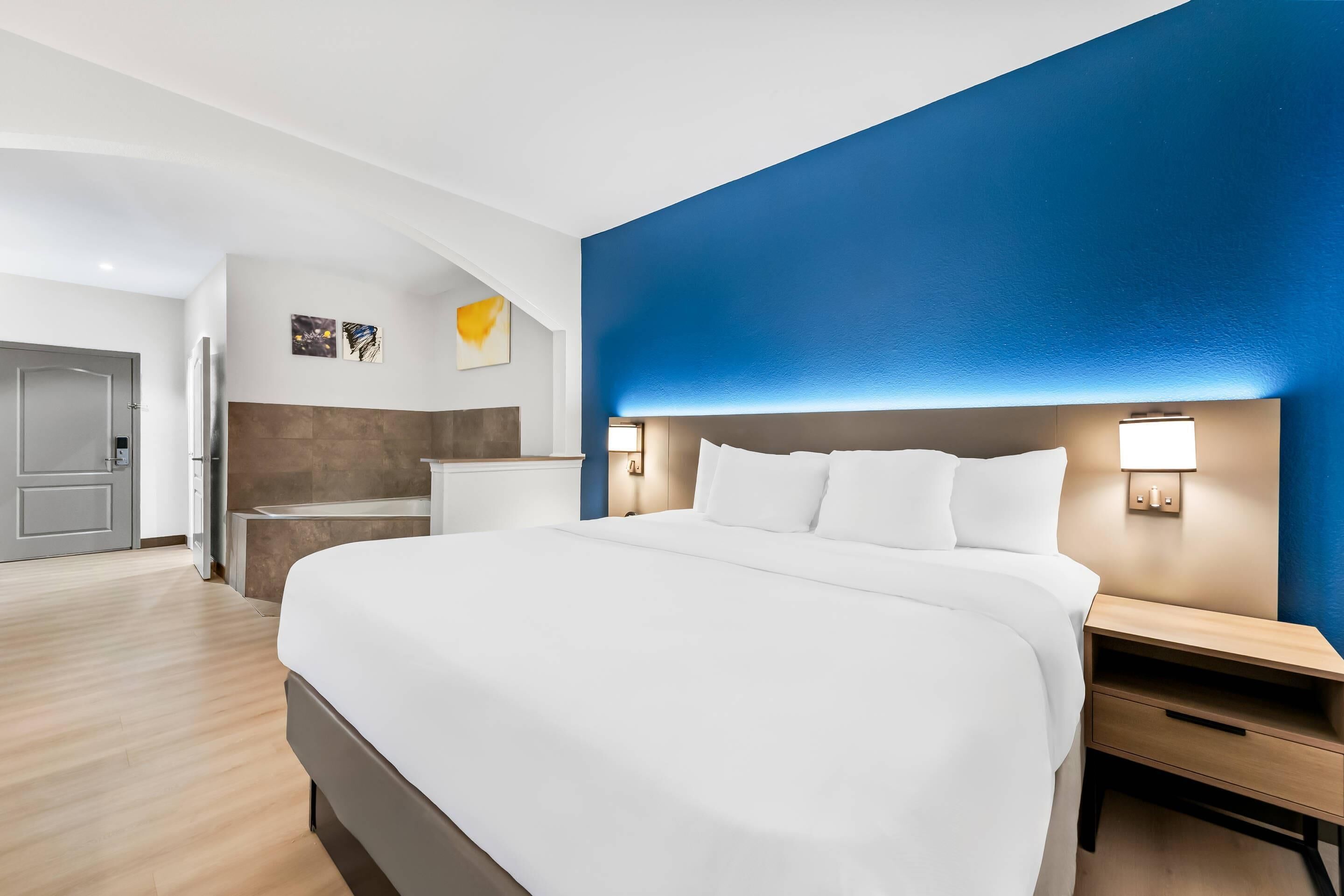 Ein modernes Hotelzimmer mit einem großen Bett, Nachttischen und einer blauen Akzentwand.