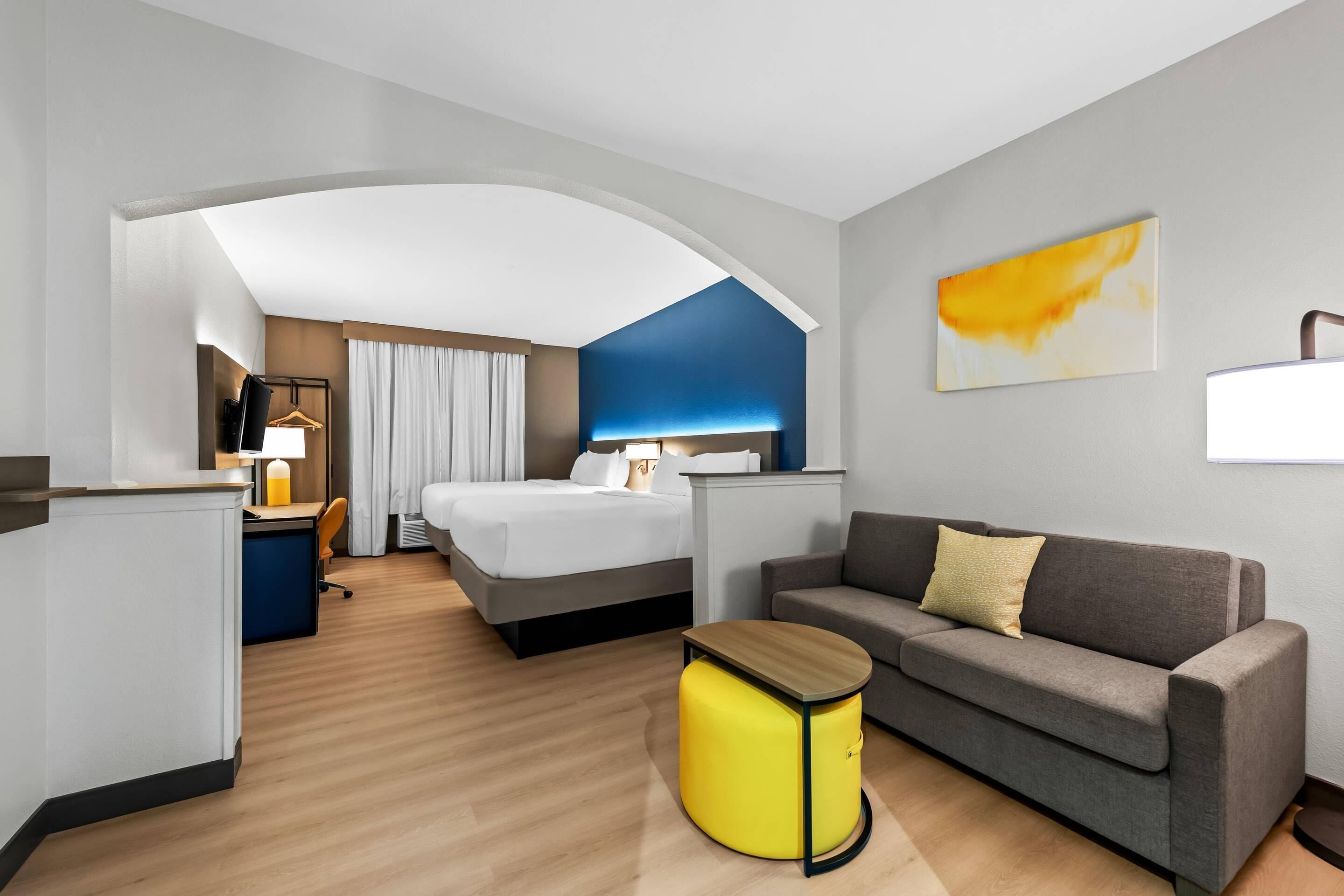 Una habitación de hotel con cama, sofá, una mesita y escritorio.