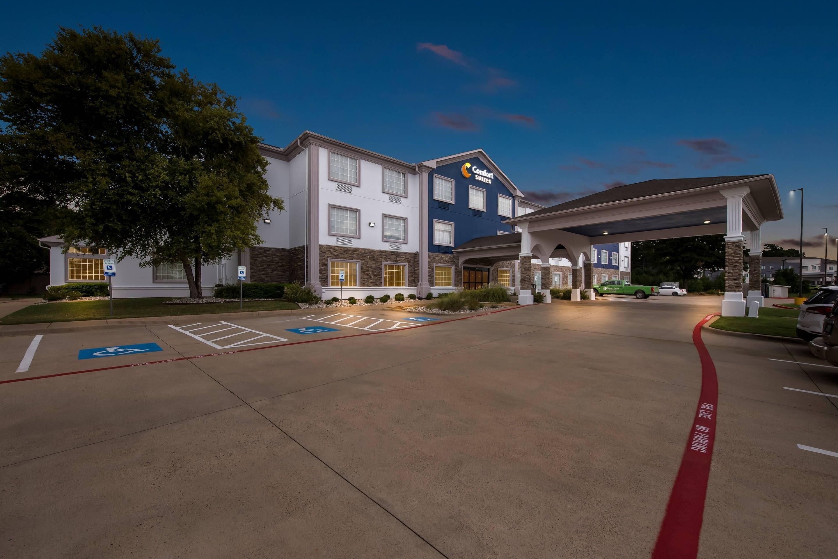 A Comfort Suites hotel with a covered parking area, handicap accessible parking, and a well-lit entrance.