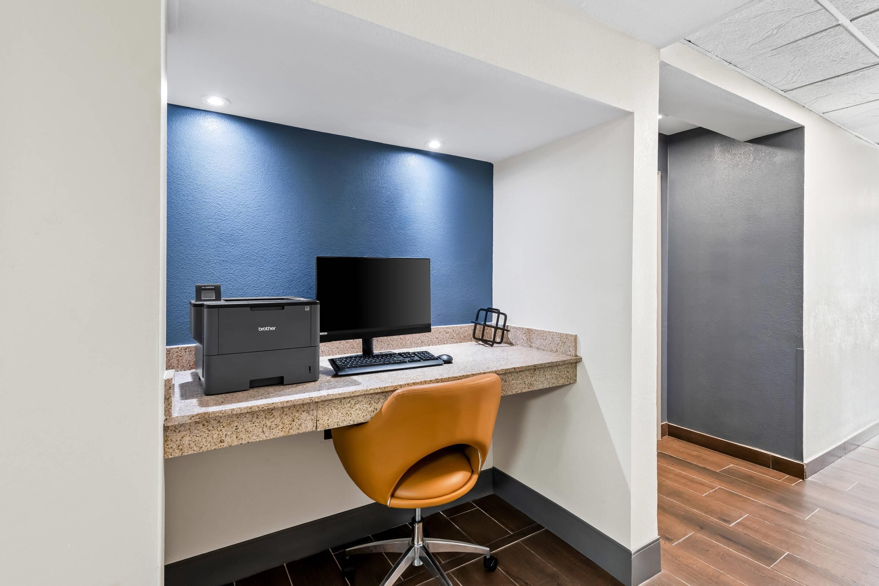 A modern office space with a desk, computer, printer, and a swivel chair.
