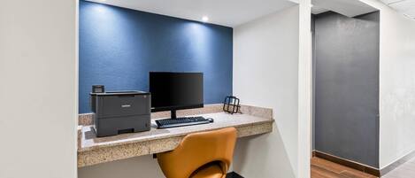 A modern office space with a desk, computer, printer, and a swivel chair.