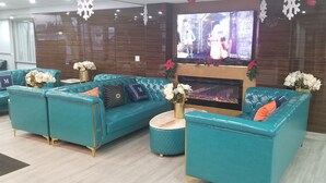 A modern living room with teal sofas, a fireplace, and a flat-screen TV.