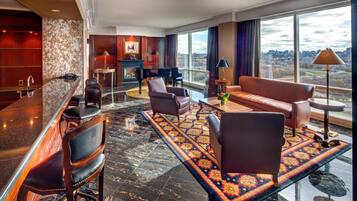 Un vestíbulo de hotel con bar, zona de estar, piano y grandes ventanales que ofrecen vistas a la ciudad.