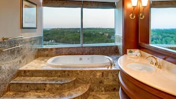 Un baño con bañera, lavamanos y un ventanal con vistas a la ciudad.