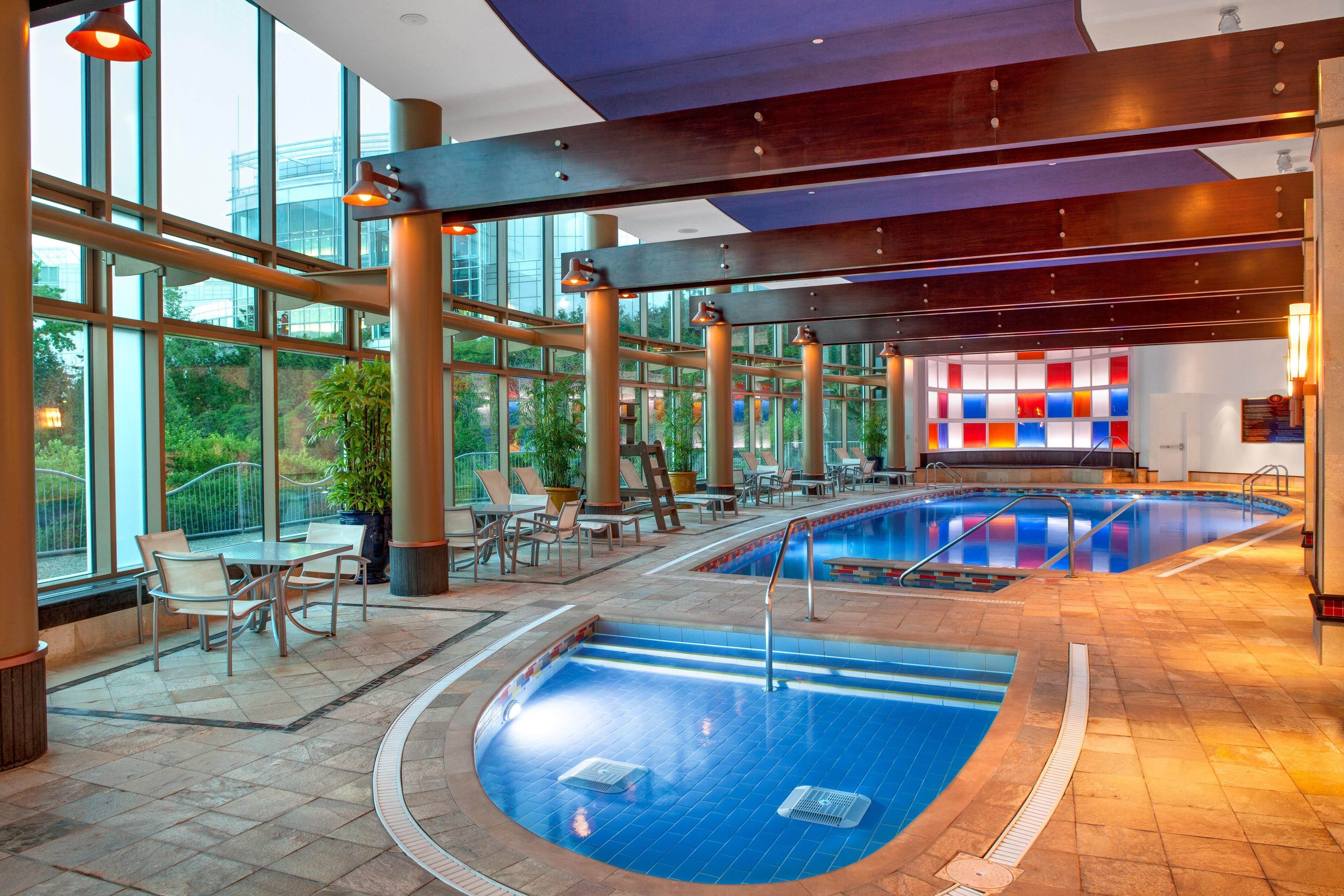 Un área de piscina interior con varias piscinas, zonas de descanso y amplios ventanales.