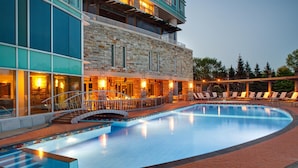 A hotel with a swimming pool, outdoor seating, and a stone facade. - Hilton Lac-Leamy (Gatineau)