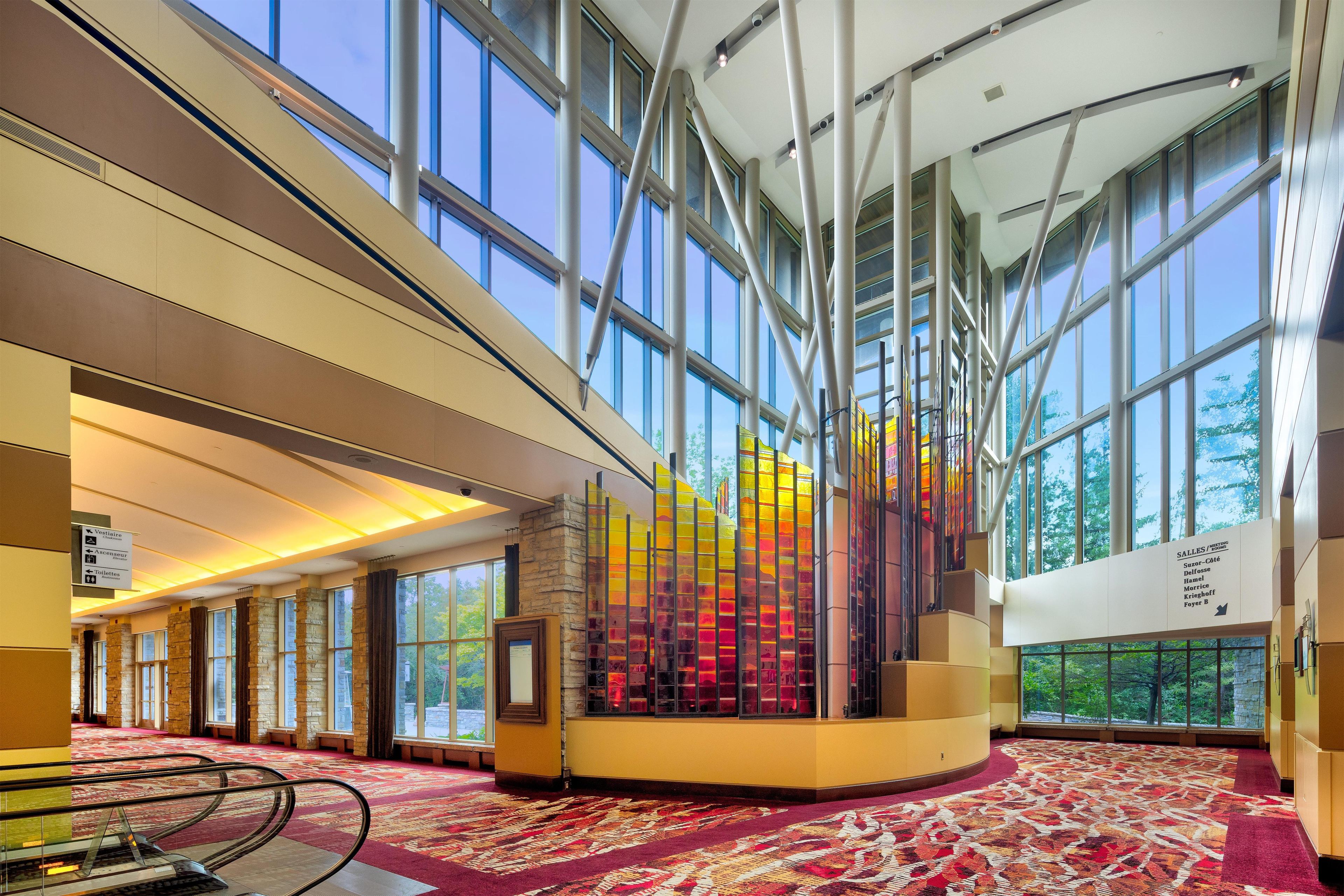 A spacious lobby with high ceilings, large windows, and a central glass art installation.