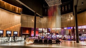 En rummelig lobby med moderne design, med et centralt siddeområde og en stor, oplyst, vertikal konstruktion.