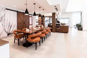 Un comedor moderno con una mesa de madera larga y sillas a juego, iluminación colgante y un ventanal que proporciona luz natural.