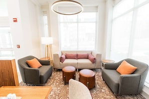 Una sala de estar moderna con un sofá, dos sillones, una mesa de centro y una lámpara.