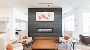 A modern lobby with a fireplace, comfortable seating, and large windows. - Hilton Garden Inn Fairfax (Fairfax)