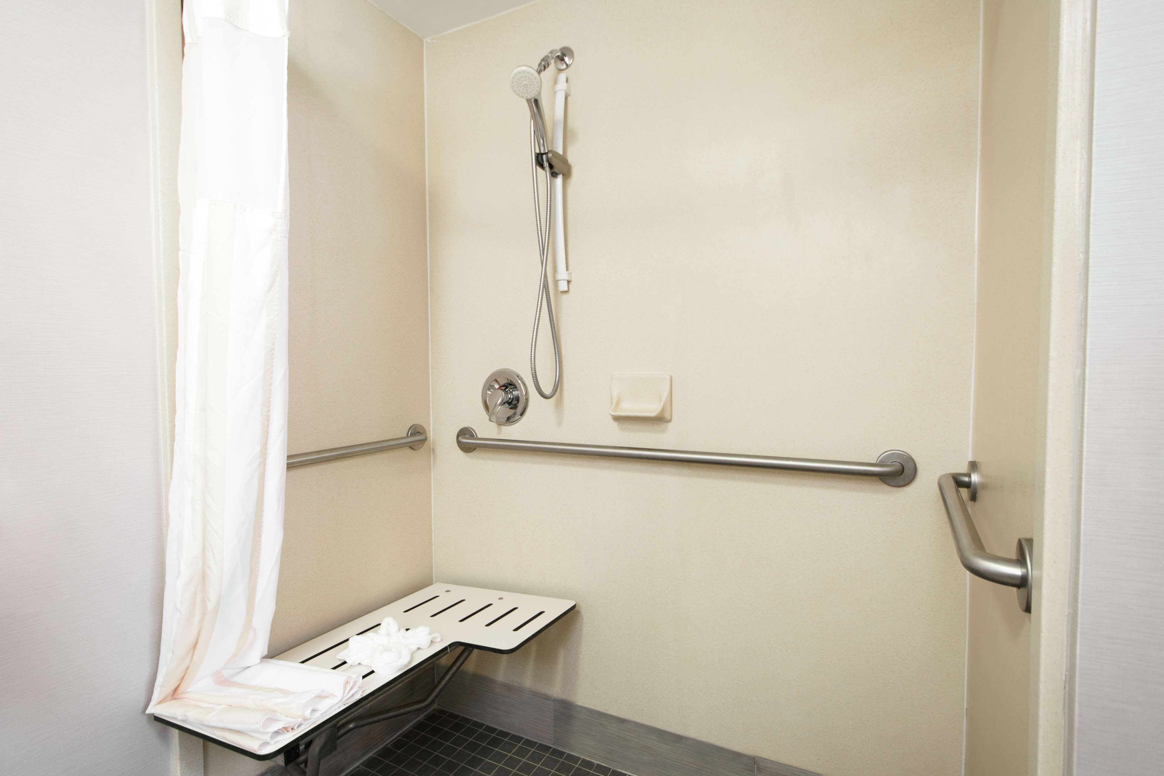 A shower area with a grab bar, a towel rack, and a showerhead.