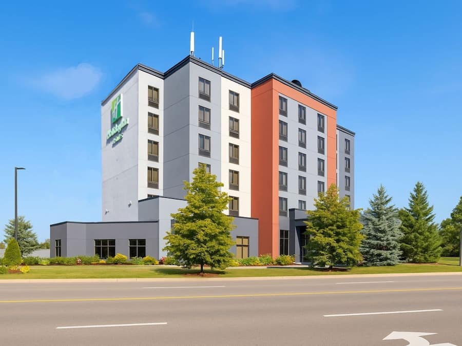 A multi-story hotel with a modern design, featuring a prominent green logo on the side.