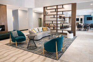 Un vestíbulo moderno con un sofá, dos sillones, una mesita de centro y una estantería.