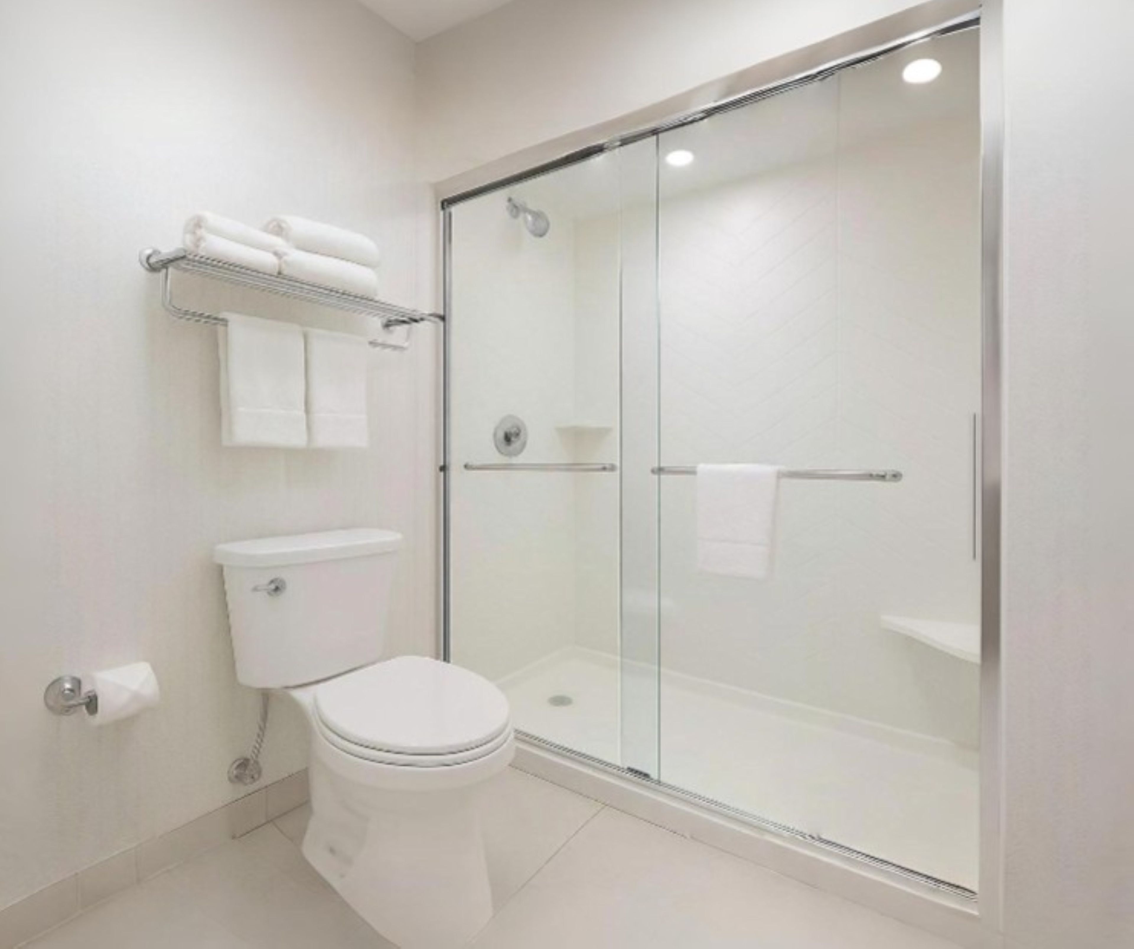 A modern bathroom with a toilet, a glass-enclosed shower, and a towel rack.