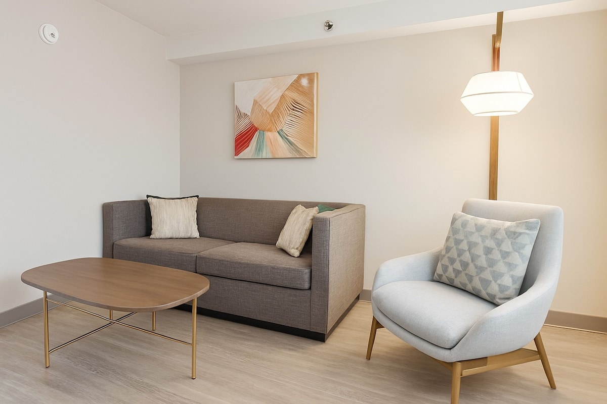 A modern living room with a grey sofa, a wooden coffee table, and a light blue armchair.