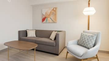 Un salón moderno con un sofá gris, una mesa de centro de madera y un sillón azul claro.
