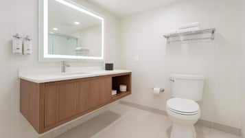 A modern bathroom with a wooden vanity, a large mirror, a white toilet, and a towel rack.