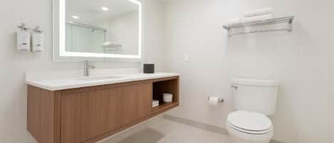 A modern bathroom with a wooden vanity, a large mirror, a white toilet, and a towel rack.