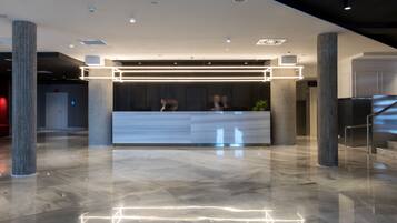 A modern reception area with a marble floor, large columns, and a reception desk with illuminated geometric patterns.