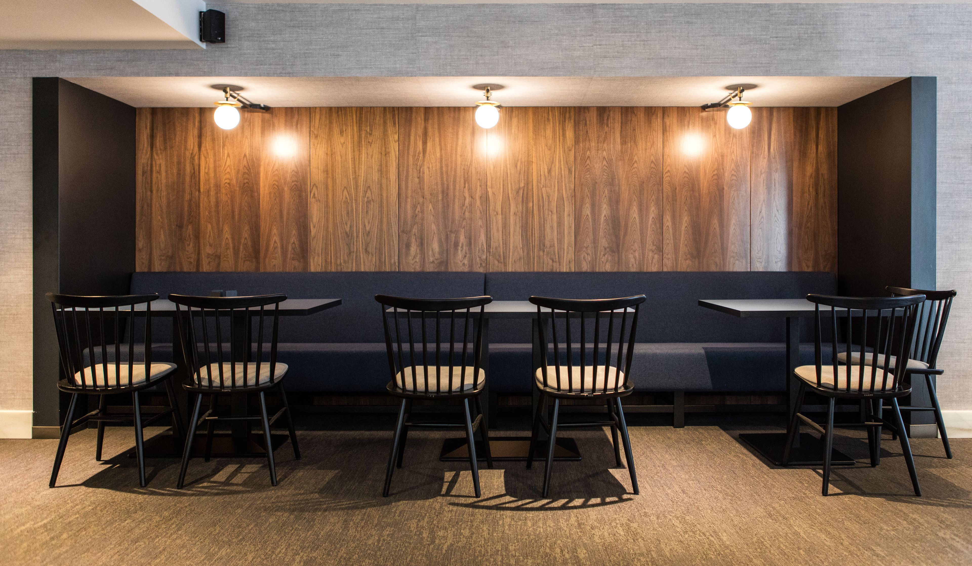 A modern seating area with wooden panel walls, black chairs, and tables.