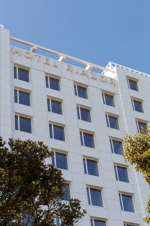 A modern hotel building with a white facade and multiple windows.